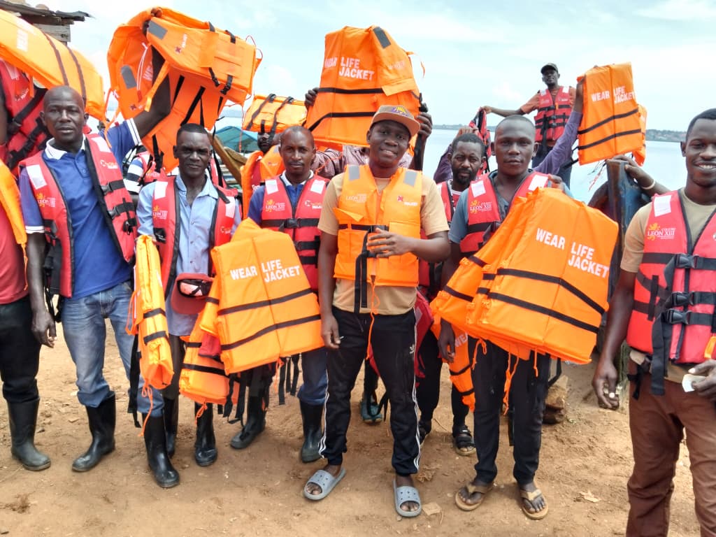 Fishermen on the shore of Lake Victoria holding the life jackets they have just received