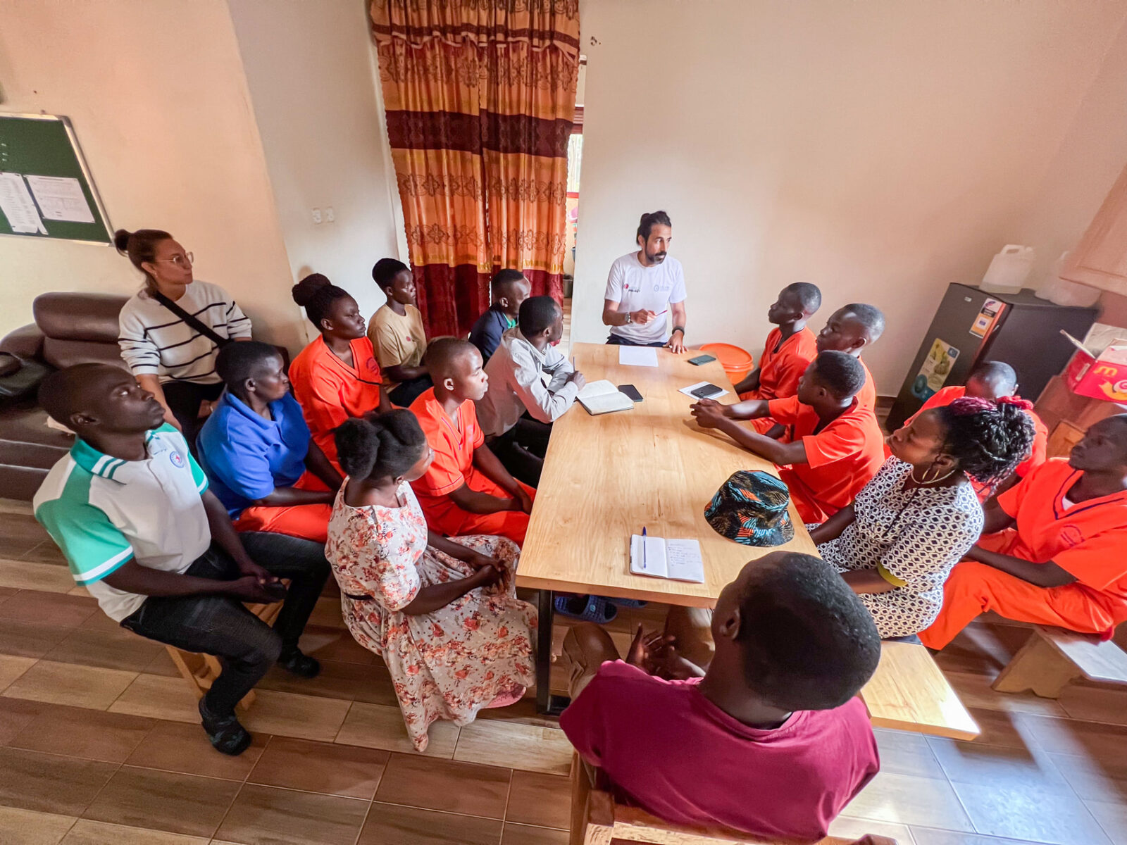 Kikaya Medical Center team meeting with staff in orange uniforms, Uganda